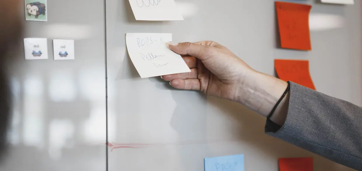 En person lägger post-it lappar på en tavla